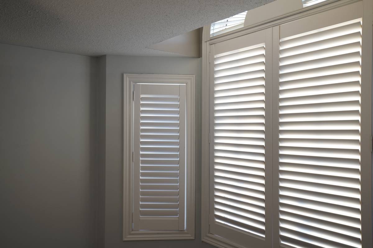 what-are-the-differences-between-blinds-and-shutters-1200px White window shutters covering a bedroom window at The Blind Guy near Spearfish, SD